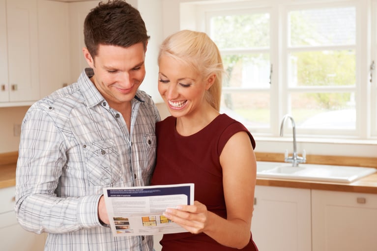 Couple standing in kitchen looking a a piece of paper with refinance rates 
